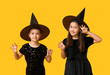 © Pixel-Shot - Cute little girls dressed for Halloween as witches on yellow background