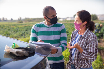 Wall Mural - Courier in protective mask invites the farmer to sign documents on the farmer field