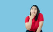 Portrait girl young woman asian chubby fat cute beautiful pretty one person wearing a red shirt is sitting, looking, and thinking idea  suspiciously and seriously  isolated blue background