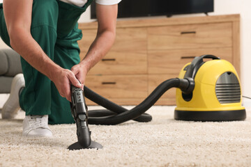 Poster - Dry cleaner's employee hoovering carpet with vacuum cleaner indoors, closeup