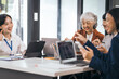 © makibestphoto - Four asian people in an office, working together on laptops, discussing tasks. annual gathering where attendees share and discuss opinions, presentation teamwork group meeting laptop in boardroom