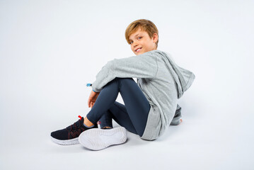 Wall Mural - Handsome young preteen athlete sitting on the floor smiling in his running tights and hoodie