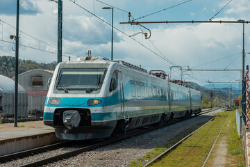 Wall Mural - Older type of high speed train is rushing through the station of Sentjur in Slovenia on a summer day. Old and neglected train tracks but nice station.