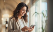 © Mangsaab - Young business woman using smartphone. Happy with good message.