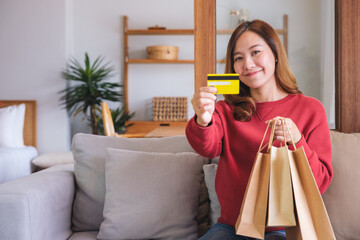 Poster - Portrait image of a woman with shopping bags holding and showing a credit card for purchasing