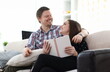 © H_Ko - Happy couple reading book on sofa. Together education concept