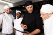 © Wavebreak Media - Multiracial male chef head showing tablet and explaining to students and in kitchen