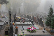 Warsaw, Poland - October 24, 2023: Graves in the cemetery on a cloudy, foggy day. Weather for All Saints' Day. Candles and flowers on graves.