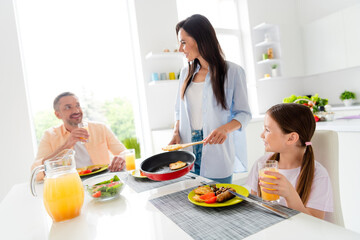 Sticker - Photo of positive family little sweet girl cheerful satisfied parents eat delicious food prepare frying pan modern dining room inside