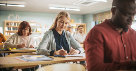 Fototapete - Middle Aged Woman Motivated to Learn New Skills During an Adult Education Course in School. Diverse Mature Students Learning in Classroom, Reading Textbooks and Writing in Notebooks.