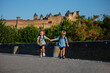 Twins holding hands and run with medieval castle on background