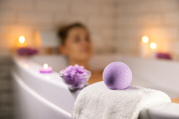 home spa. woman relaxing in bathtub in candle light and using bath bomb and sea salt crystals for body skin moisturizing