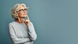 © Caphira Lescante - Senior woman with a finger tip on her cheek, thinking, happy with herself and her life. Best-ager, baby-boomer with grey short hair on a blue background.