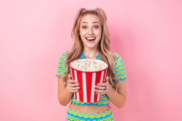 Poster - Portrait of impressed ecstatic girl with tails dressed colorful suit hands hold popcorn at cinema isolated on pink color background