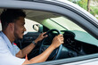 © ibragimova - guy in a car. a young guy in a white shirt with a watch on his hand drives a car in a big city during the day, a guy in a white car sits behind the wheel