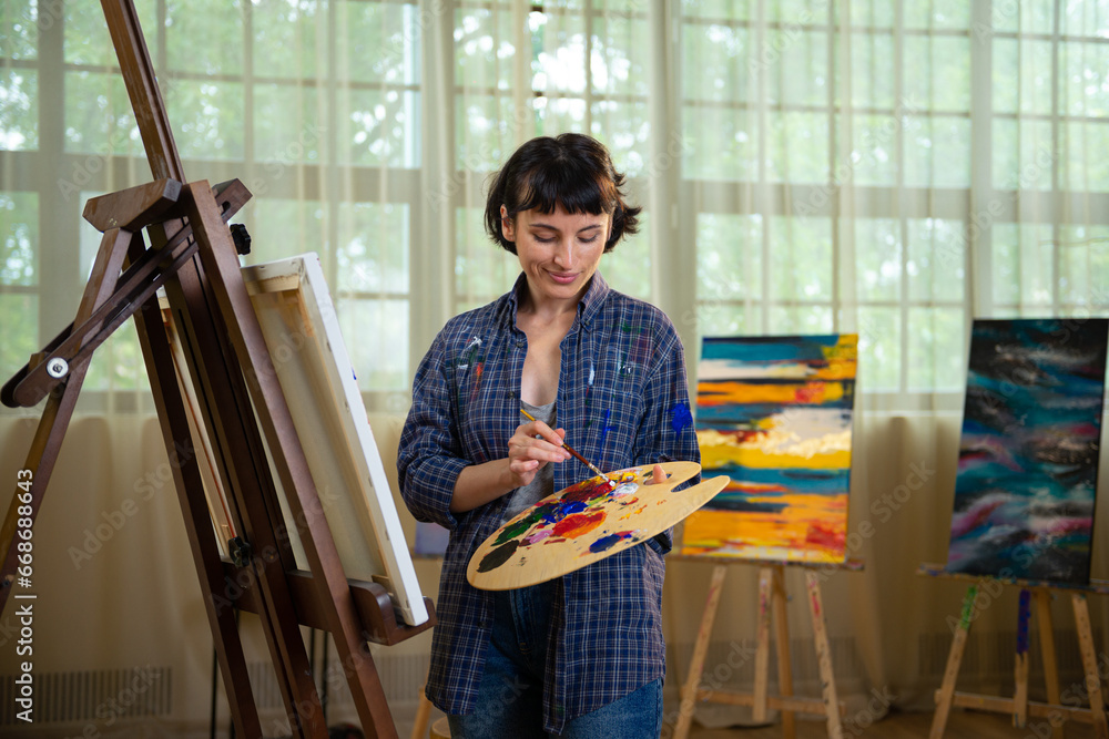 beautiful young female painter sitting on floor and drawing picture in ...