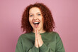 Happy cheerful excited successful woman with redhead and curls clapping hands with surprised facial expression after winning prize or getting present, isolated against pink background