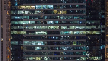 Wall Mural - Office buildings windows illuminated at night timelapse. Glass architecture, corporate building at evening with glowing lights