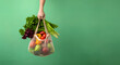 Human hand holding bag with fresh vegetables over green background