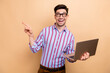 © deagreez - Photo of young promoter cheerful marketer directing finger empty space wireless computer services isolated on beige color background