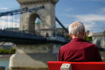 Budapest, Hungary - October 1, 2023: A senior tourist with Szechenyi Chain Bridge and Buda Castle in the background. Széchenyi lánchíd, Budavári Palota