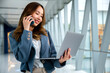 © sorapop - Professional woman using laptop and cellphone to multitask in airport, staying connected while traveling