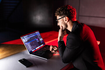 Young man mobile developer writes program code on a computer, programmer work in office.