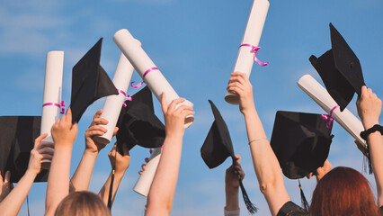 Graduates connect diplomas and caps on a sunny day.