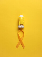 Yellow ribbon with toy rocket, childhood cancer awareness day symbol