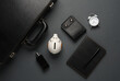 Leather suitcase with piggy bank, notebook, purse, alarm clock and perfume bottle on a dark background. Business concept. Top view