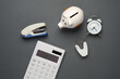 Calculator with a piggy bank, staplers and an alarm clock on a dark background. Business concept