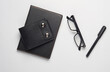 Notebook with black leather cover and purse, eyeglasses on gray background. Top view