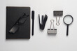 Notebook, stapler, eyeglasses, binders, magnifying glass on white background. Black stationery objects. Top view. Flat lay