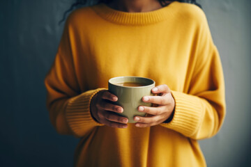 Wall Mural - Woman in cozy sweater holding a big cup with coffee close up