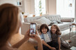 © Marko Geber - Mother capturing a cheerful moment of her children on smartphone at home