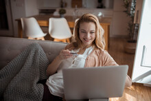 Smiling Young Woman Holding A Credit Card With A Laptop On The Couch At Home