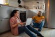 © Marko Geber - Mixed Race Couple Discussing Finances in the Kitchen