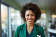 Professional doctor dark skinned woman head shot photo portrait, confident curly hair smiling female employee in hospital in green jacket, health care, medicine, surgery. Stethoscope on her neck.
