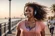 Happy Afro-American woman running on the waterfront with headphones on a sunny day