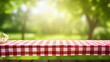 © rorozoa - Picnic setup with a tablecloth over a table, set against a blurred green outdoor scene.