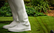 close up of sculpture of white trousers and shoes with green background