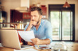 © Geber86 - Concerned young man reading through bank statements at home