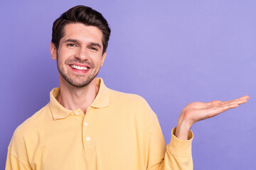 Sticker - Photo of positive cheerful man dressed yellow shirt holding arm empty space isolated purple color background