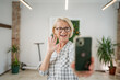 © Miljan Živković - One woman mature caucasian female at home or office use mobile phone hold smartphone take selfie photos self portrait or make a video call daily routine copy space