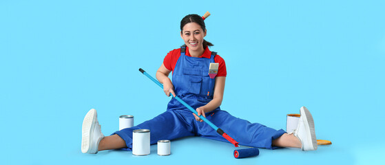 Poster - Female Asian decorator with paint roller and cans on light blue background