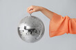 © Pixel-Shot - Female hand with disco ball on grey background