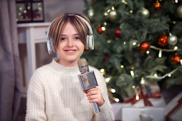 Sticker - Cute little boy in headphones with microphone at home on Christmas eve