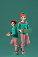 Sticker - Cute little children in elves costumes with Christmas gift boxes on green background