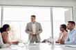 © insta_photos - Happy senior Indian business man director boss ceo leading employees team meeting presenting company strategy working with diverse colleagues during board discussion in office conference room.