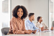 © insta_photos - Happy African American company employee, smiling young business woman sitting at diverse team office meeting. Professional businesswoman company employee leader with tablet in board room, portrait.
